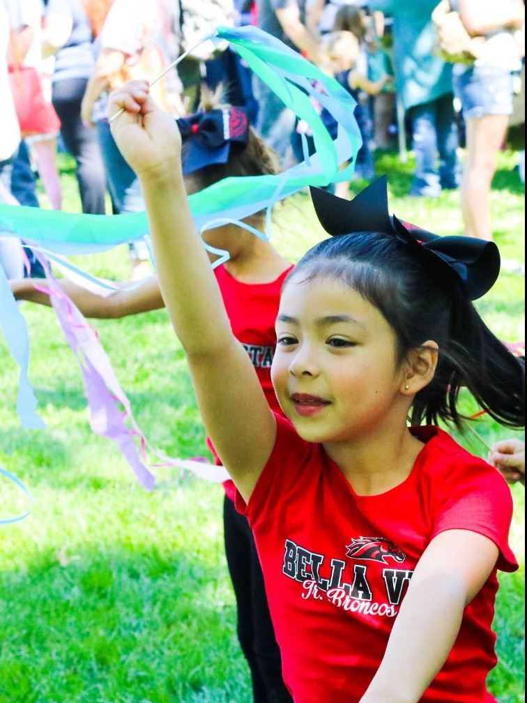 small girl dancing with ribbon wand